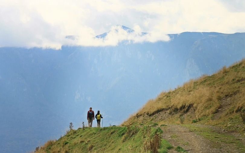 two people standing on a mountain looking over the valley