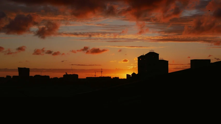 the sun is setting over the city in a cloudy sky