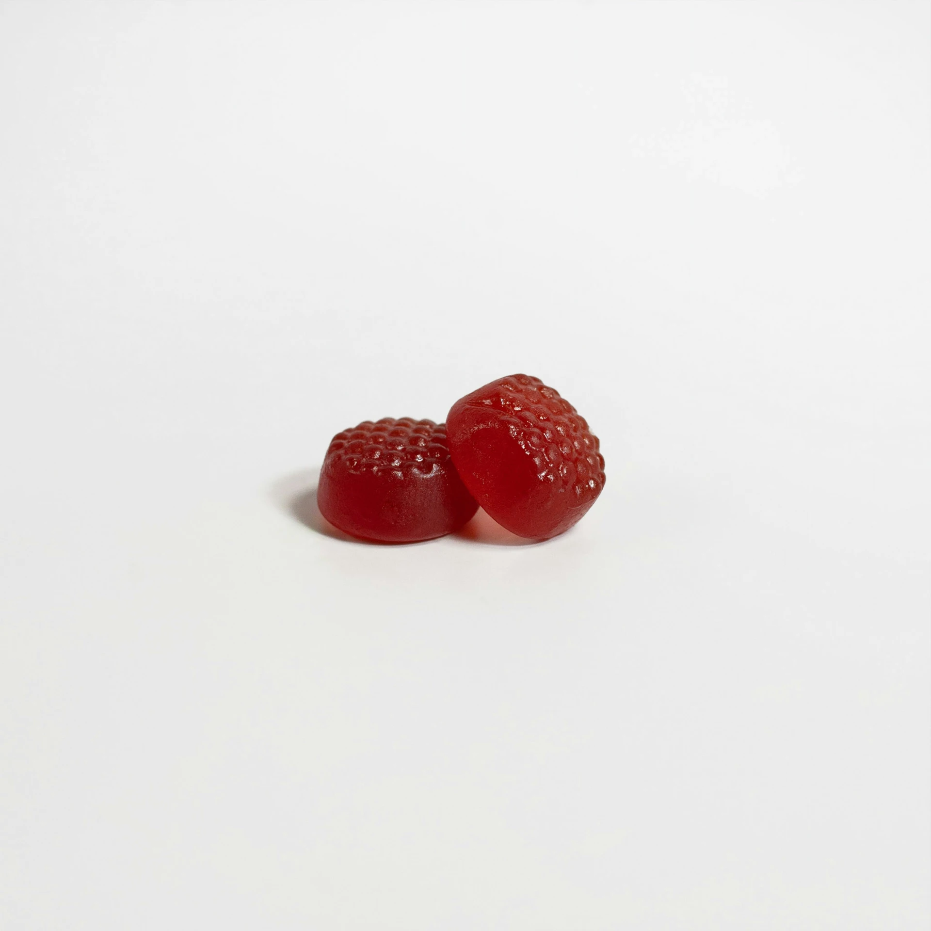 two pieces of red strawberries sit on a white surface