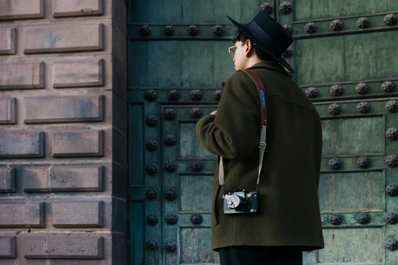 a man standing outside in front of an ornate green door