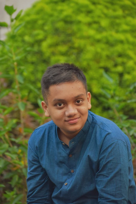 a young man with dark hair and blue shirt posing for the camera