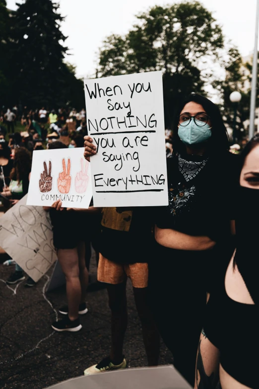 two people holding signs at an event that read when you say nothing