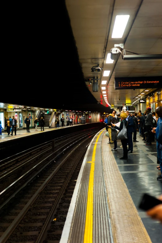 several people wait at the train station for their train