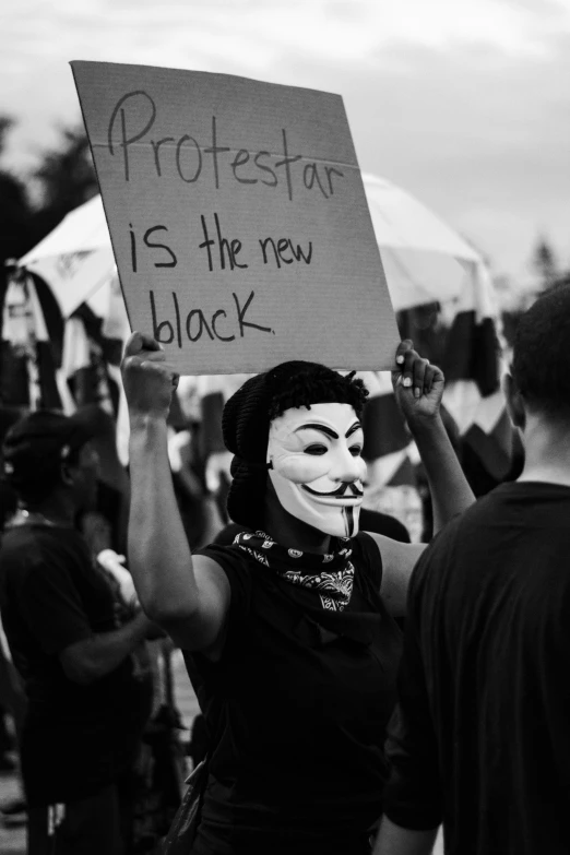 a protester with a mask on holding a sign