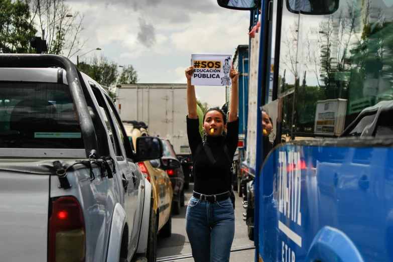 a person holding up a sign and standing in front of some cars