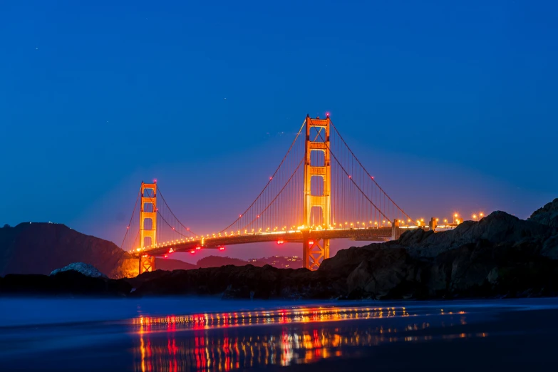 the bright lights of the golden gate bridge reflected in the water