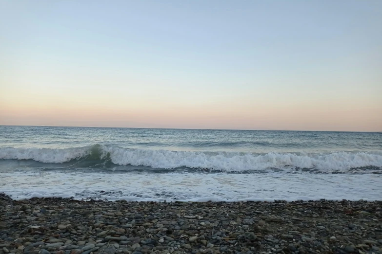 waves crash into the shore during sunrise at beach