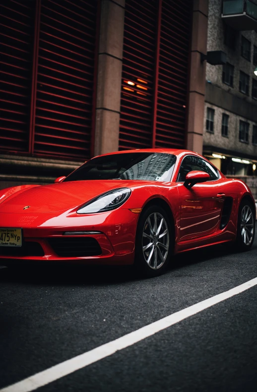 red sports car on the street next to the building