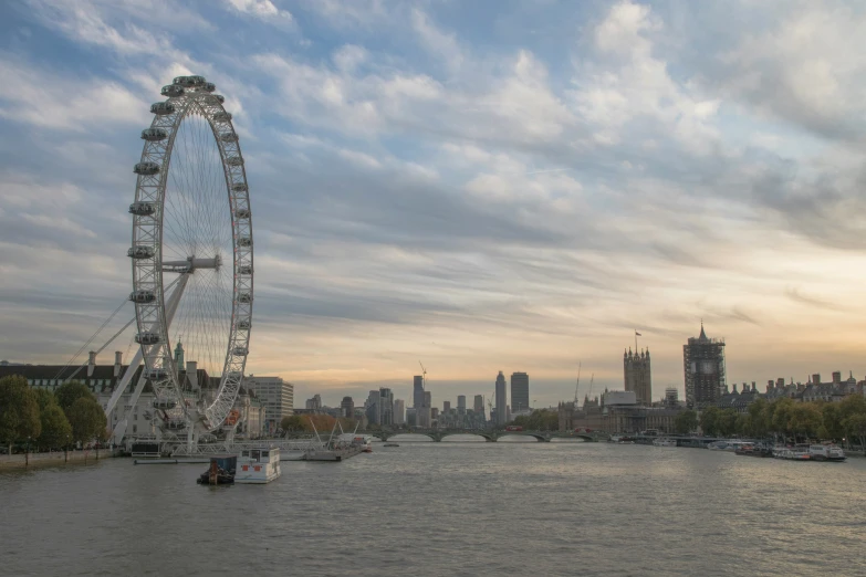 a ferris wheel sitting on top of a river next to a city