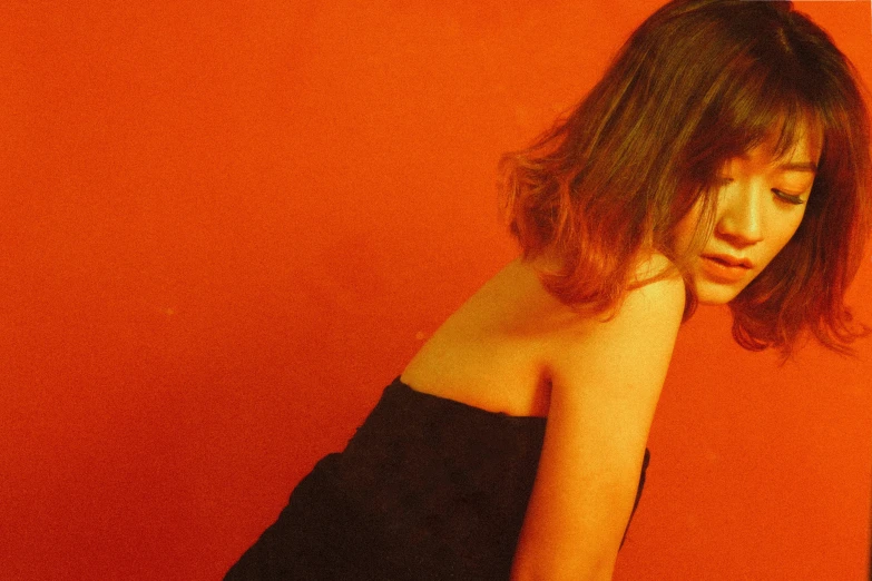 a woman is sitting by herself against an orange wall