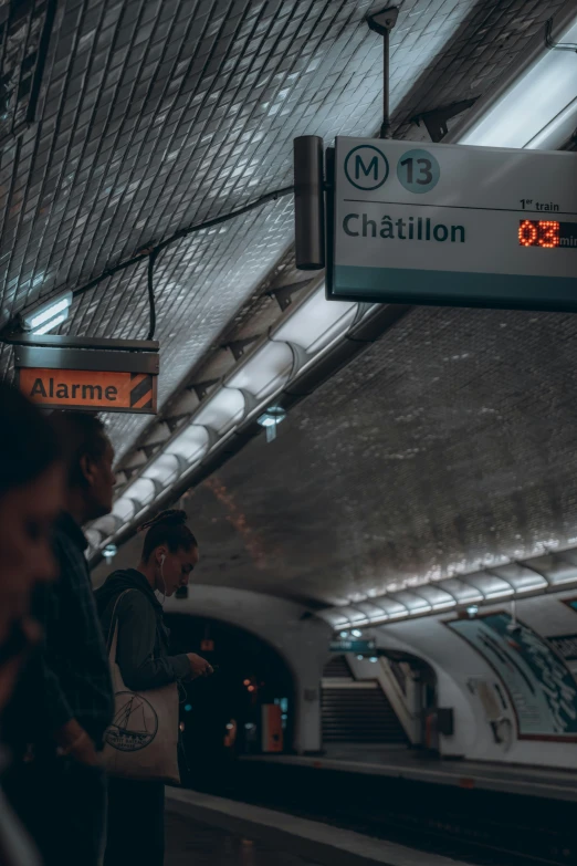 a subway station has neon lights above a man waiting for his train