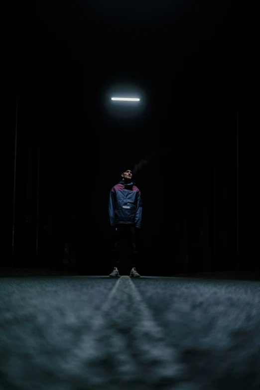 a man standing in a dark room with his hand on his hip