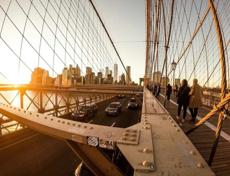 the brooklyn bridge during sunset with a few people walking across it