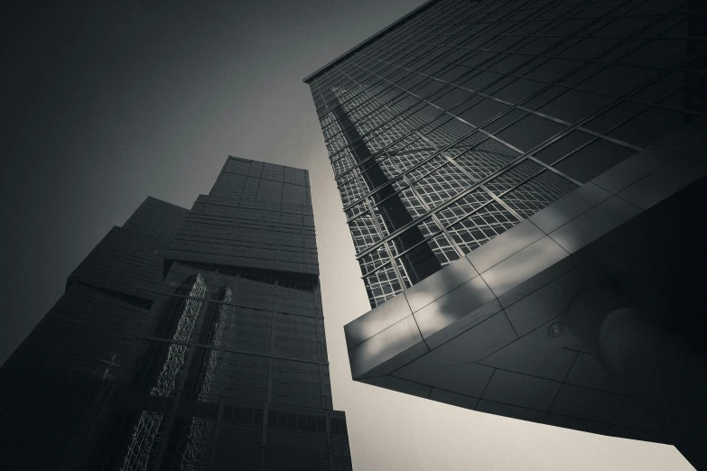 two skyscrs in black and white with a cloudy sky behind them