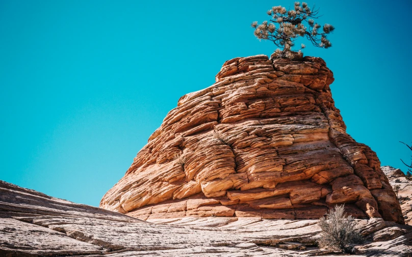 a rock formation in the desert with plants growing at the base