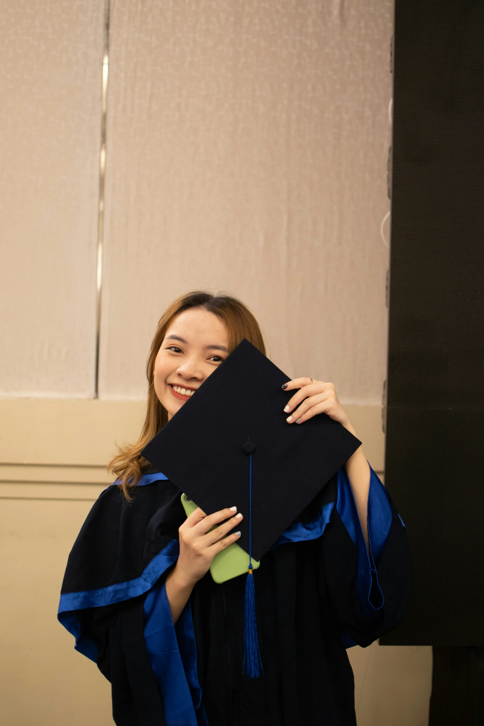 a young woman holding a black cap and gown