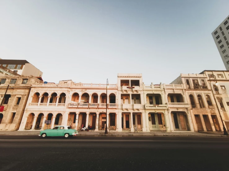 a car driving in front of a building with balconies