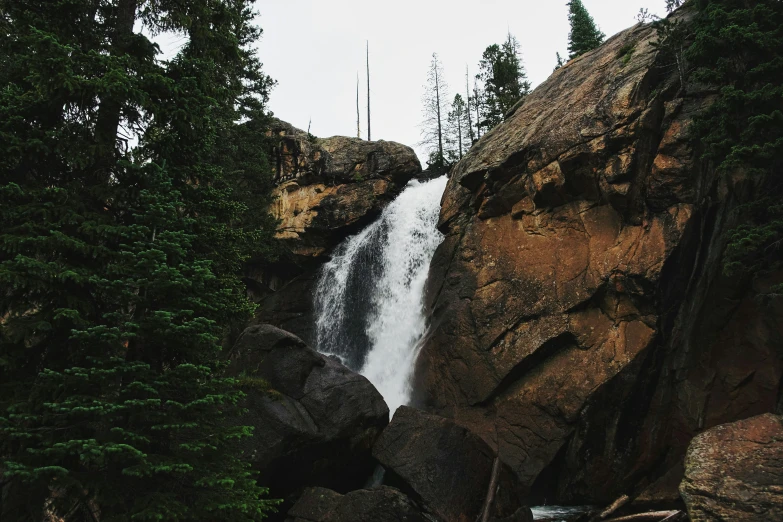 a waterfall flowing into a rocky river surrounded by trees