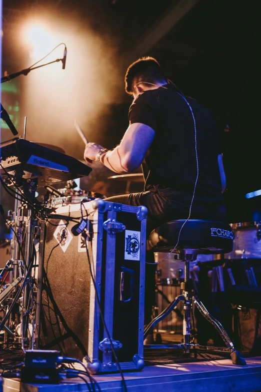 man playing drums in front of microphones on stage