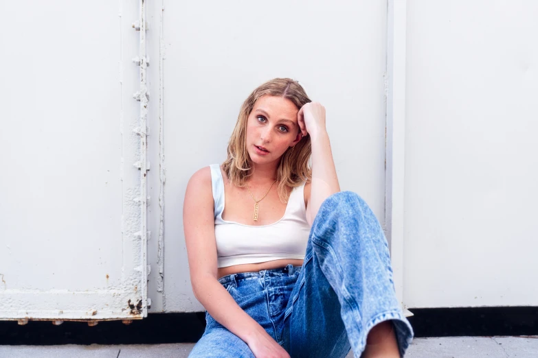 a female wearing jeans sitting on a floor next to a door