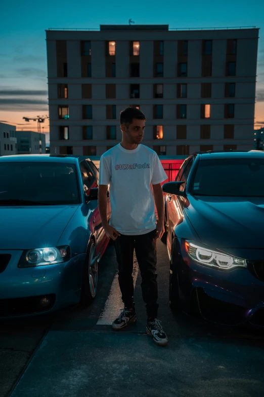 a man standing near parked cars and a large building