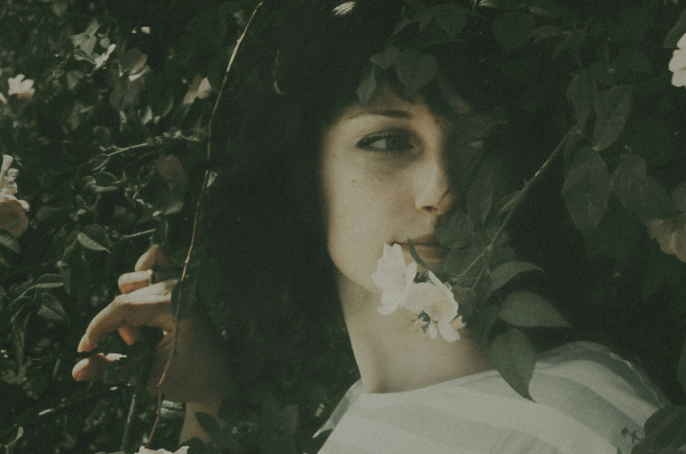 a woman holding flowers in her mouth while she stares straight ahead