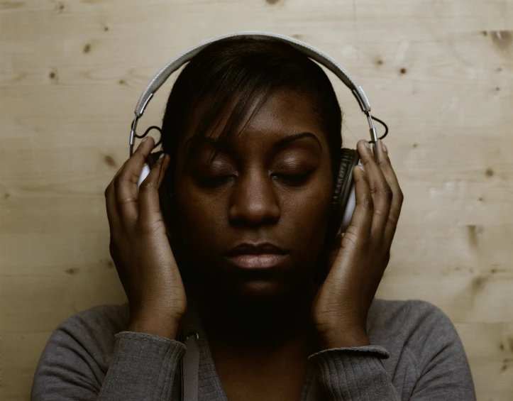 a woman in grey shirt holding two headphones