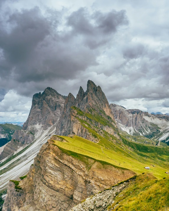 mountains are seen under clouds and some light green grass