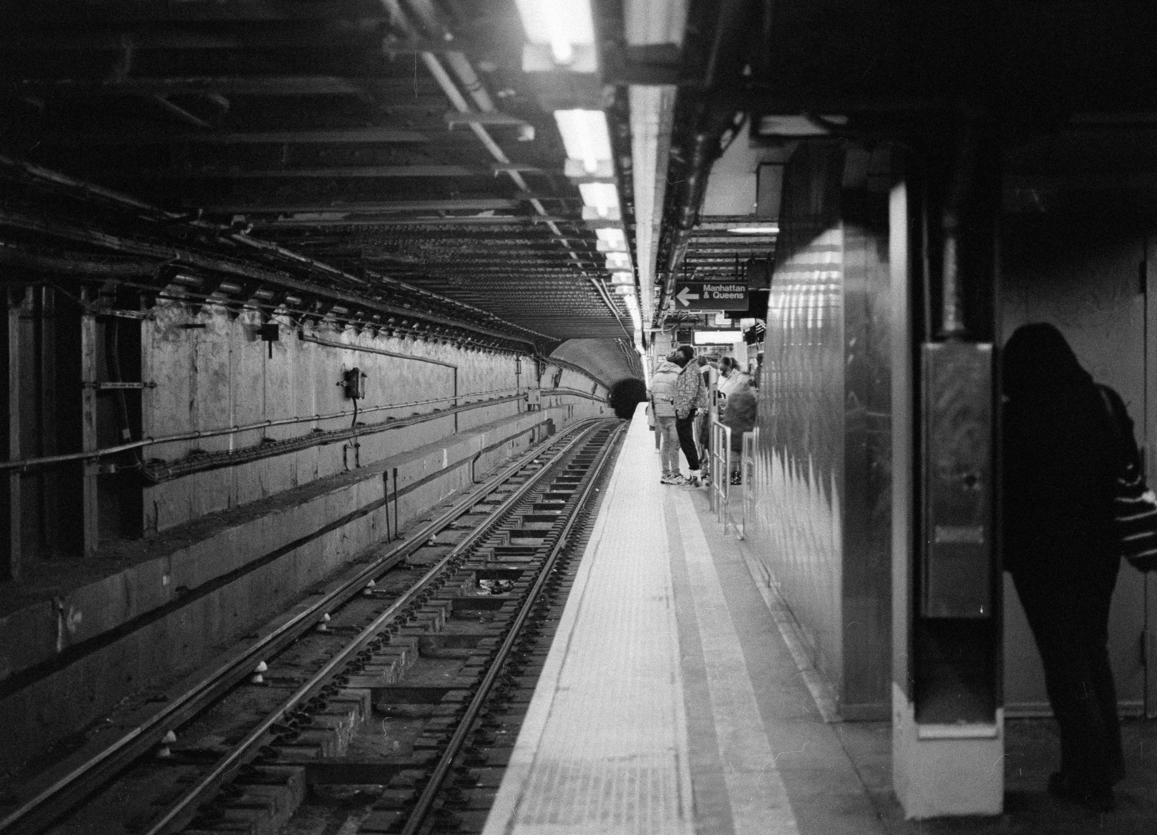 a long train on a metal track next to people