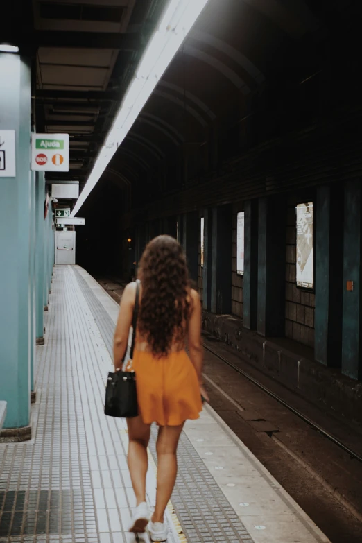 a woman is walking alone holding a black purse