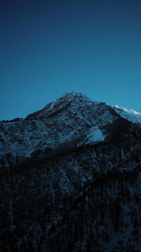 a mountain that is covered with snow under a blue sky