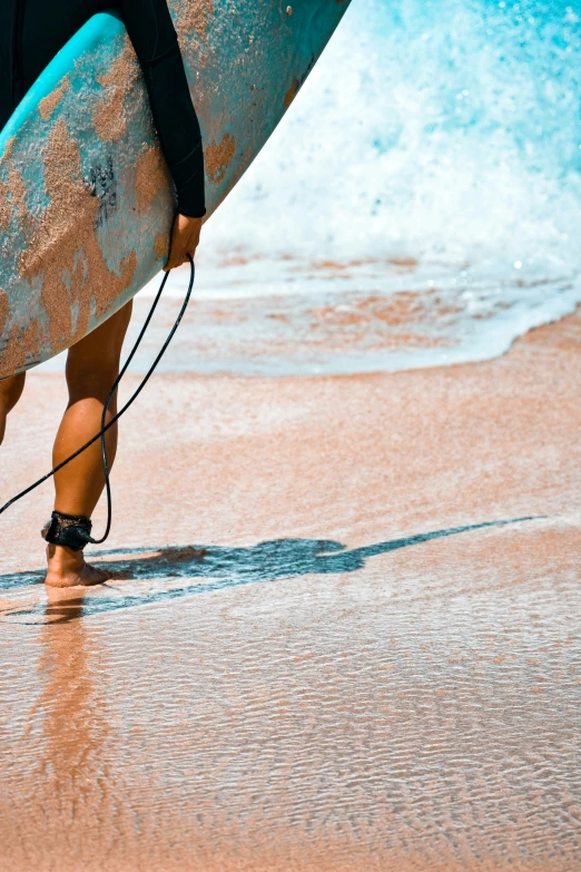 a surfer holds his surfboard in one hand and wades in the other