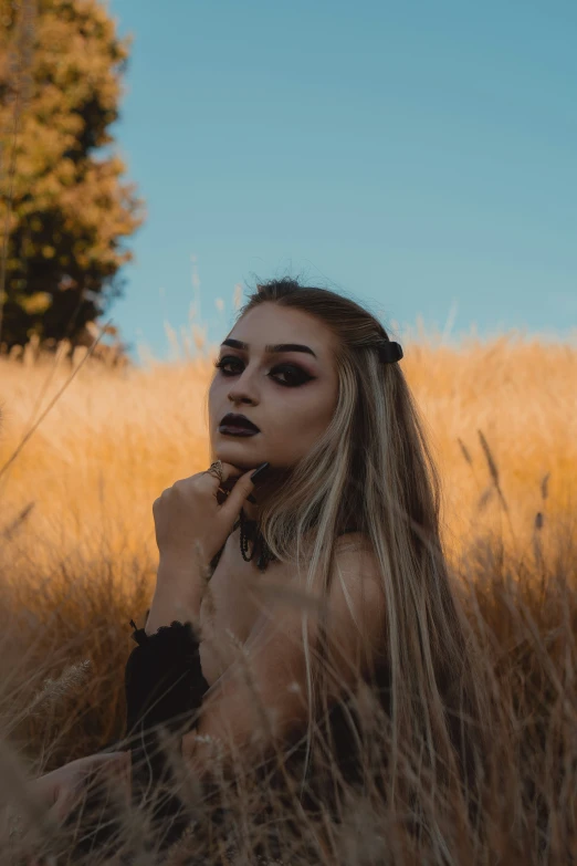 a girl with black makeup standing in a field