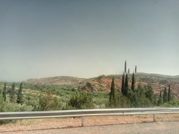 a view of a hill and trees from behind a car