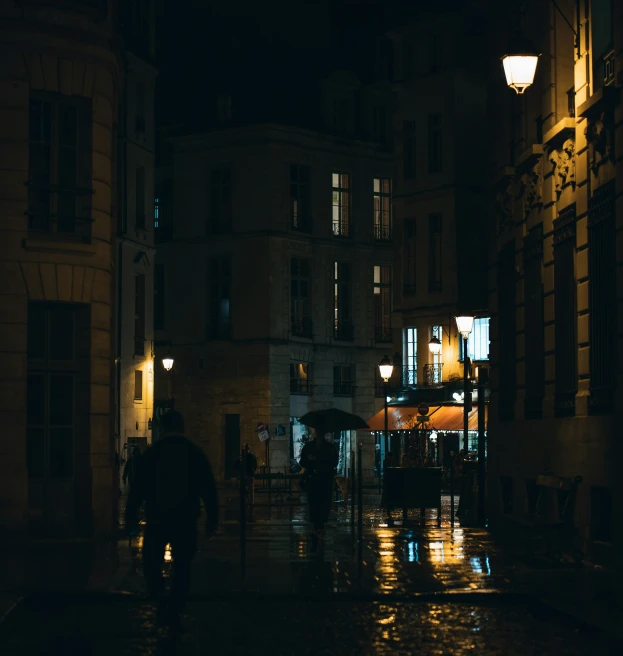 people walking past a couple of buildings at night
