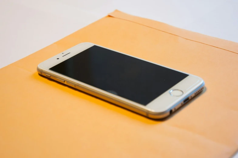 a smart phone is sitting on a plain tan envelope