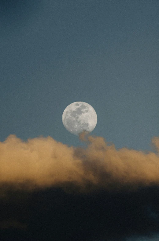 a large full moon visible between dark clouds