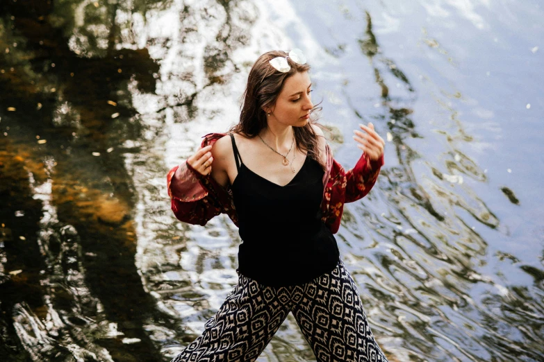 a beautiful young woman standing in front of a body of water