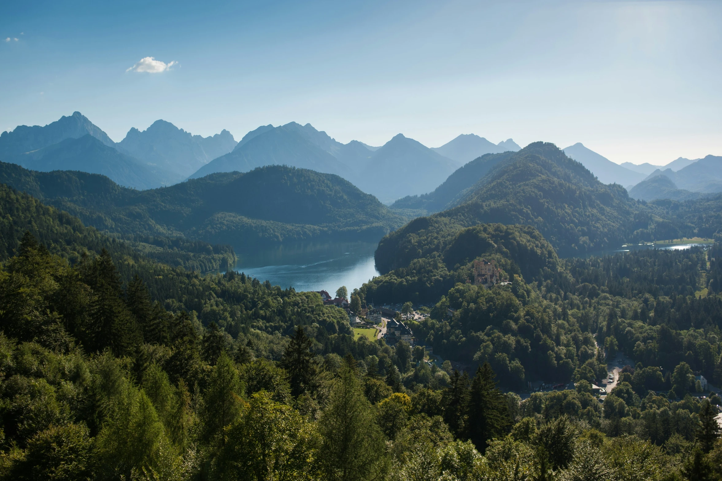 mountains with a lake, trees and buildings in them