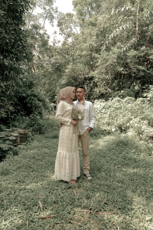 a couple standing together in the grass near a river