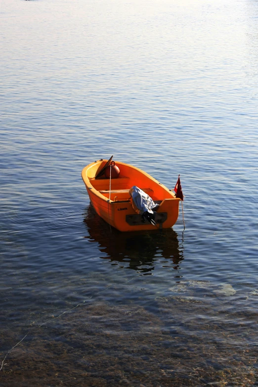 an orange row boat with three people on it floating in the water