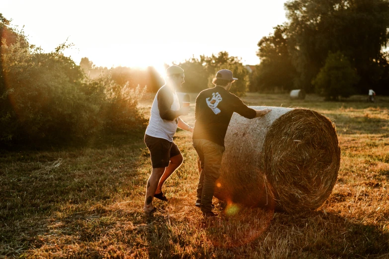 two men carry a bale of hay together