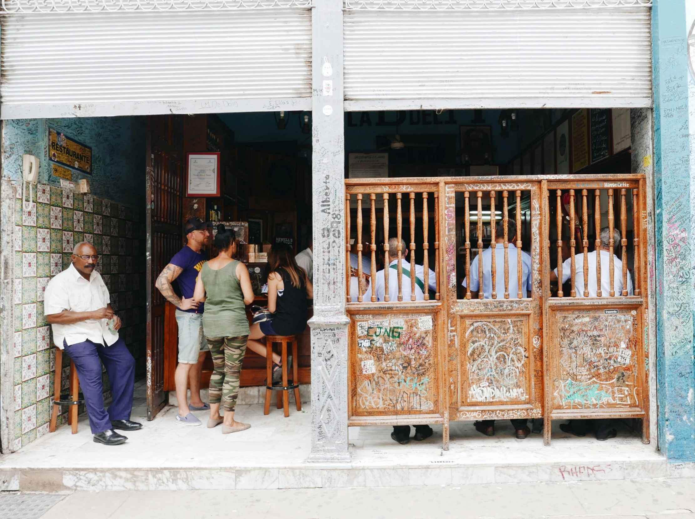 people stand outside of the doors of a restaurant