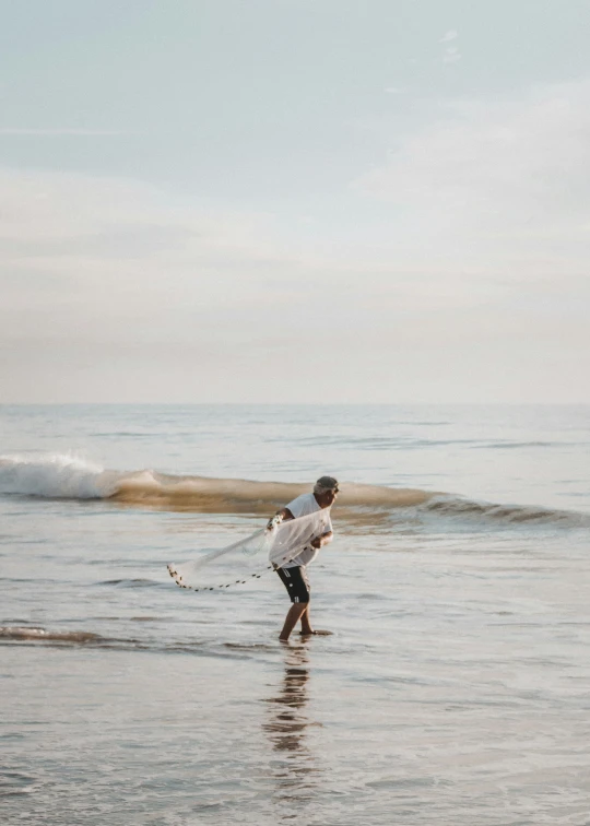 a man walking in the ocean with a white surfboard