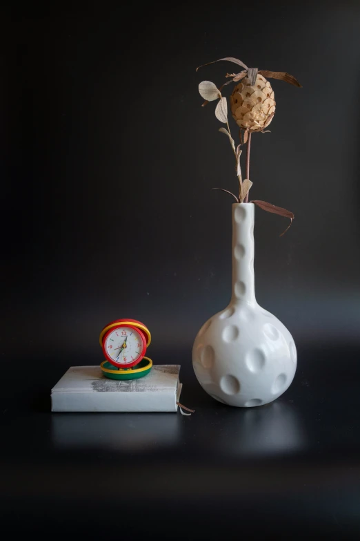 a small clock and vase on a table