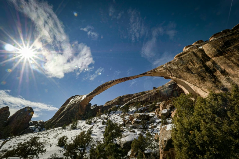 the sun peeks through the arch in the rocks