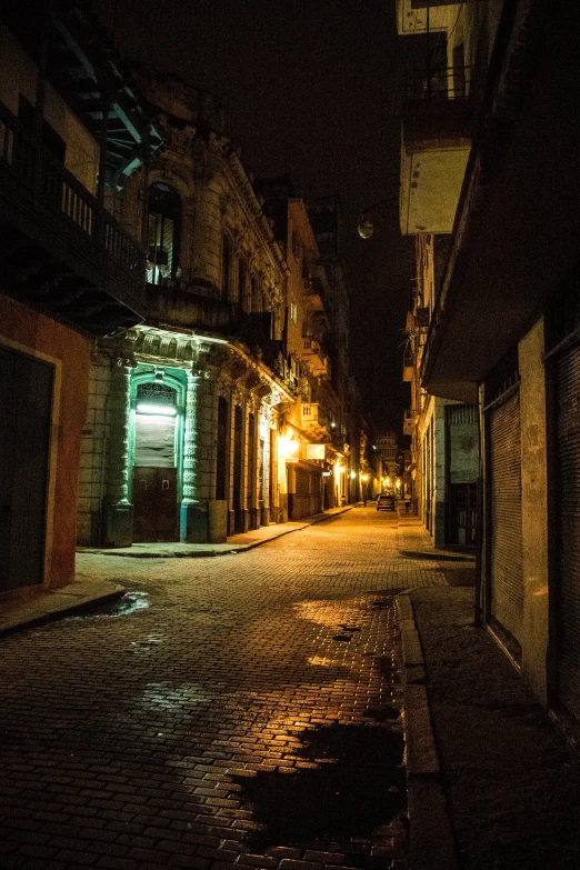 a wet street with buildings at night time