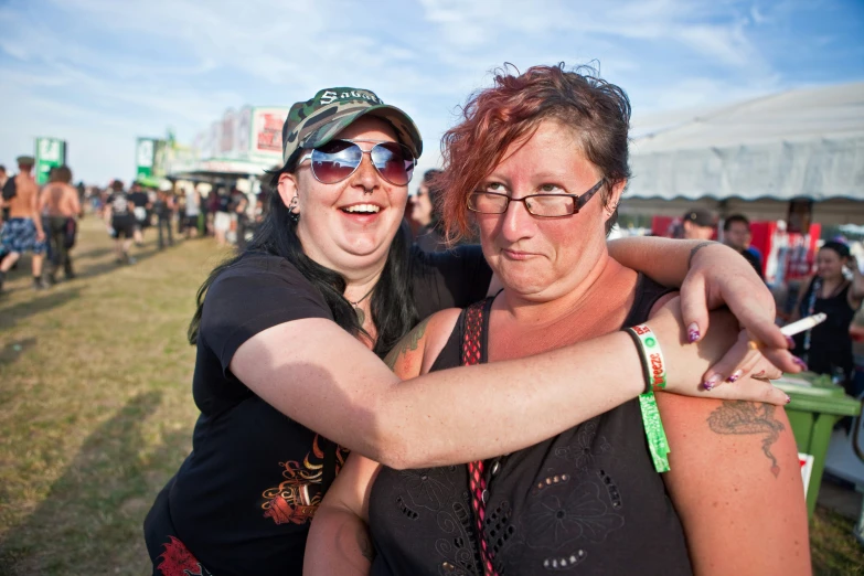 two women hugging each other at an outdoor festival