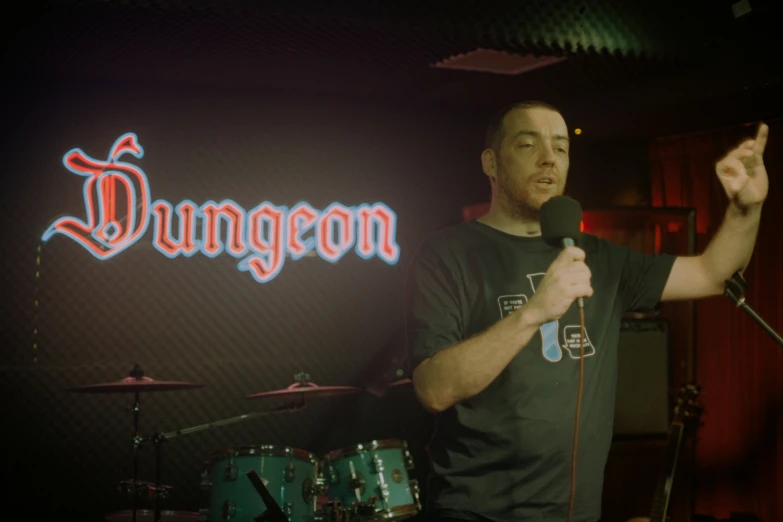 a man standing in front of a microphone with one hand up