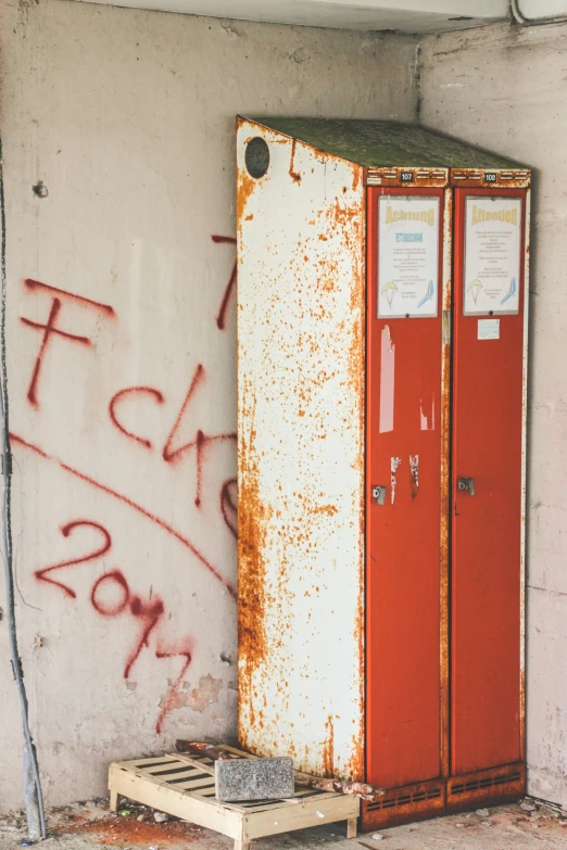 an old orange and white freezer sitting in front of a wall